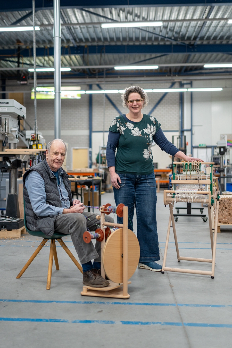 Loes and Jan Louët Feisser in the workshop with a spinning wheel and a shaft loom
